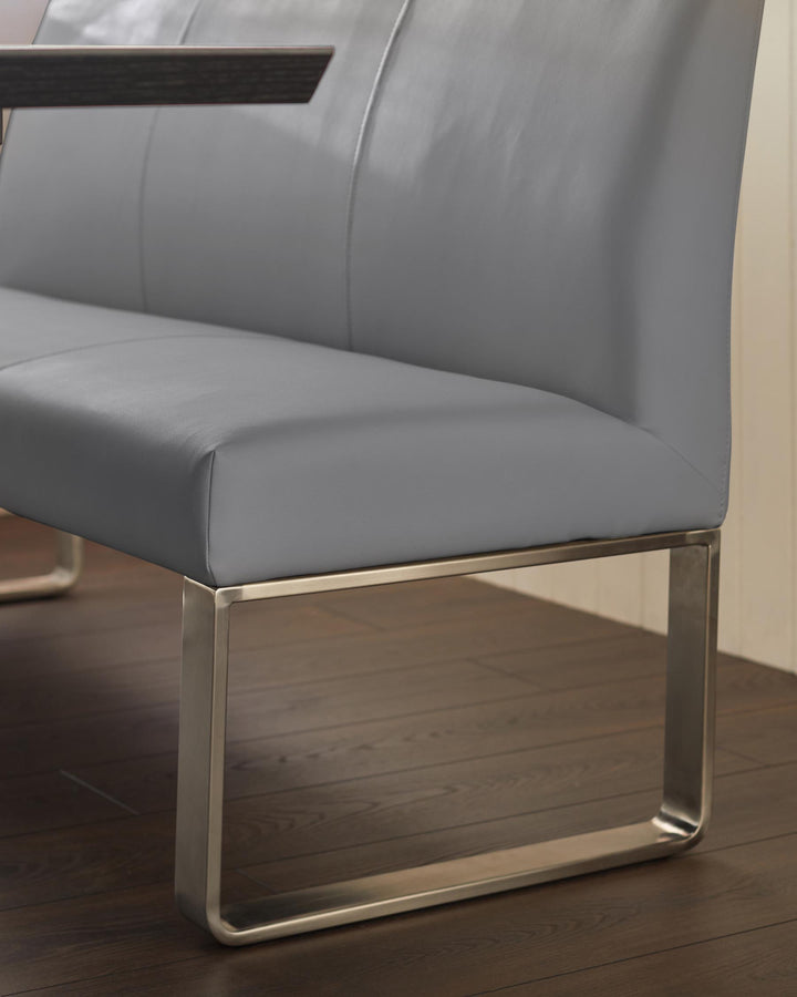 A grey leather dining bench with sleek, modern, silver legs, perfect for contemporary dining spaces.