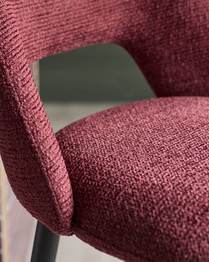Close-up of a claret-coloured chair featuring a textured fabric on the seat and armrest, offering a tactile and inviting appearance.