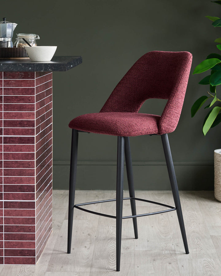 A stylish red bar stool with black legs sits next to a kitchen island.