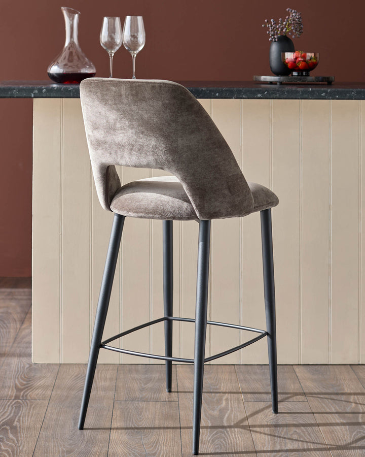 Upholstered bar stool in mink velvet with black metal legs, positioned in front of a kitchen island.