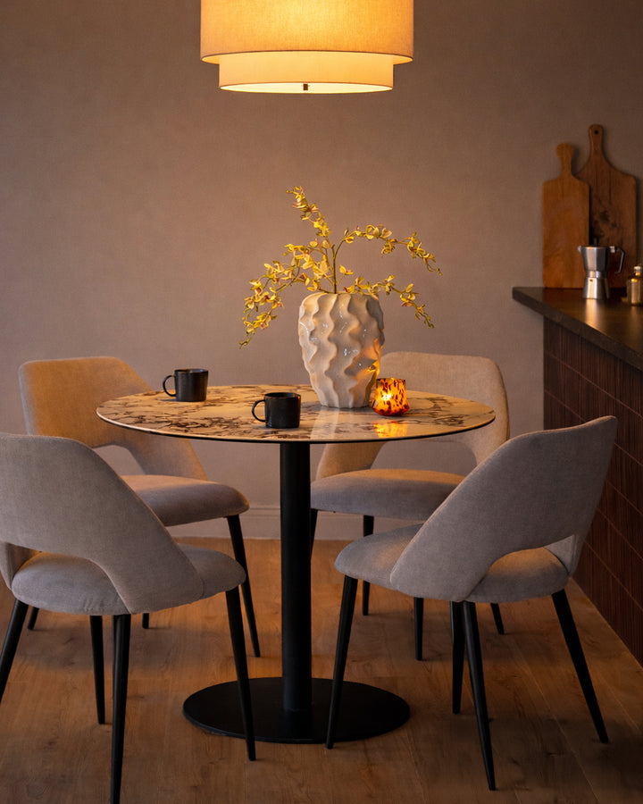 Lottie mid-grey fabric dining chair with curved backrest and black tapered legs, shown at round table.
