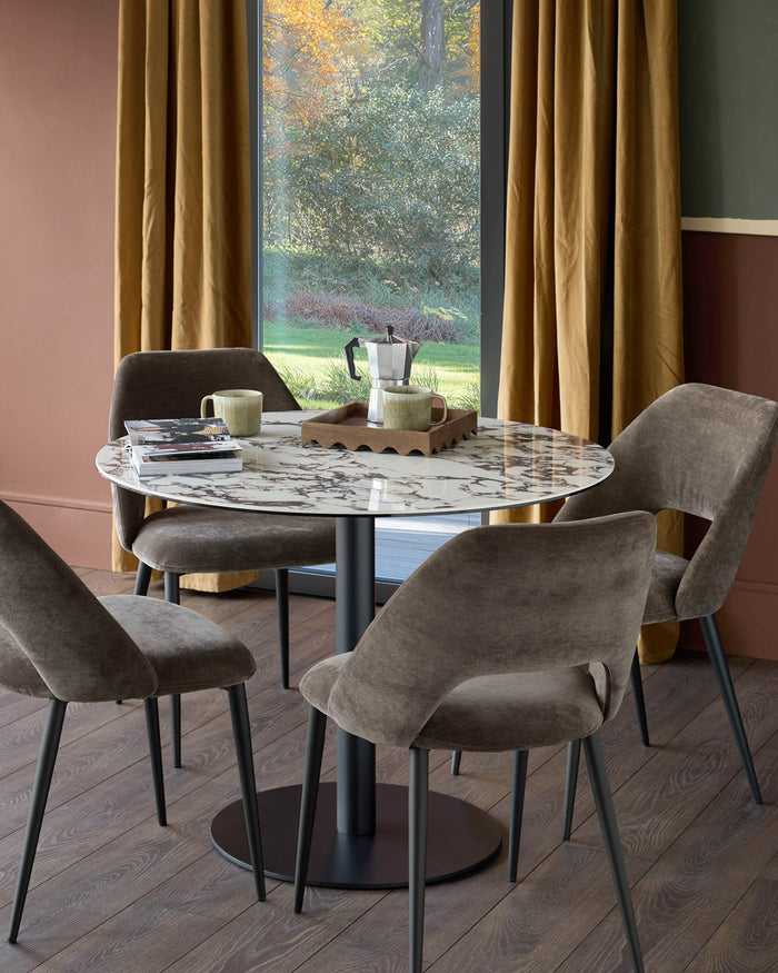 A round marble dining table with brown chairs and black legs creates an inviting space for dining.