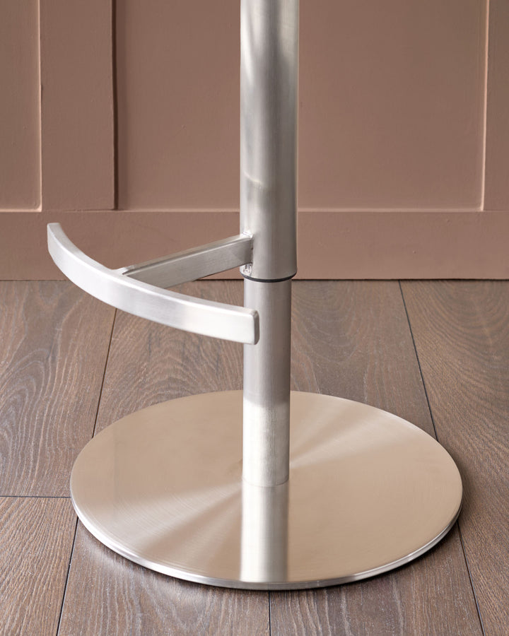 White gas-lift bar stool with curved handle, shown from side angle against beige wall and wood flooring.
