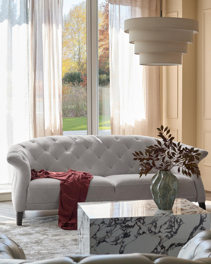 A comfortable, stylish living room featuring a grey sofa, marble coffee table, and statement light fitting.