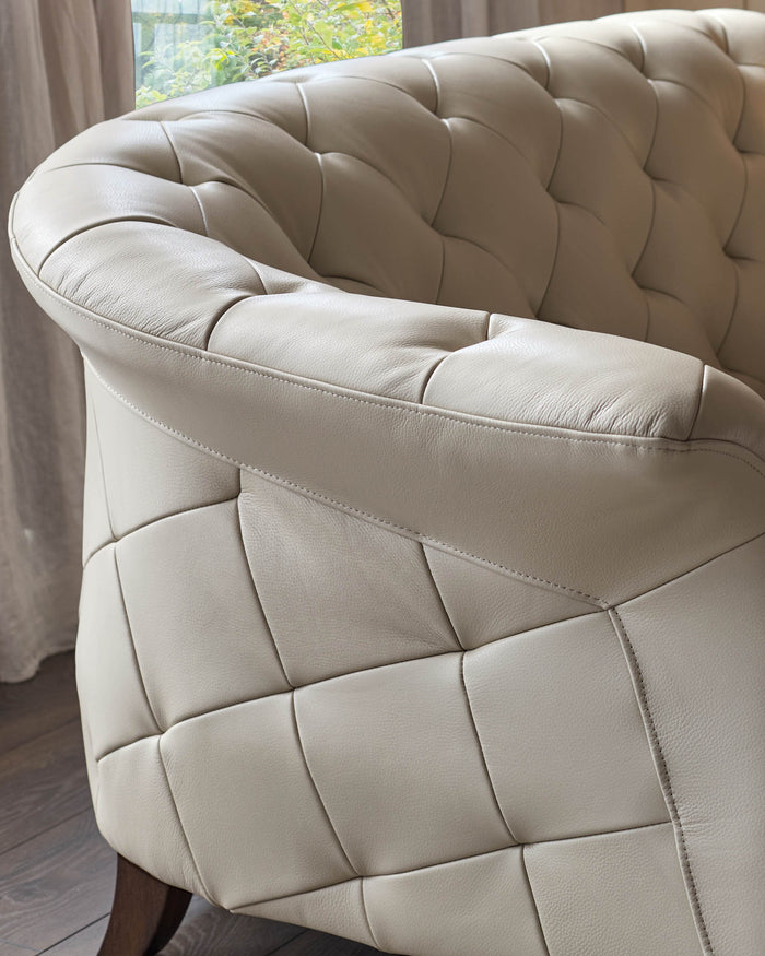 Close-up of a luxury leather sofa with a buttoned back and arm, showcasing its elegant design and craftsmanship.