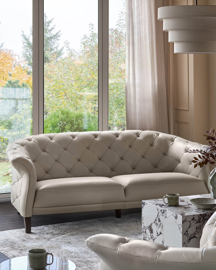 Elegant cream sofa with buttoned detailing, paired with a marble side table in a stylish living room setting.