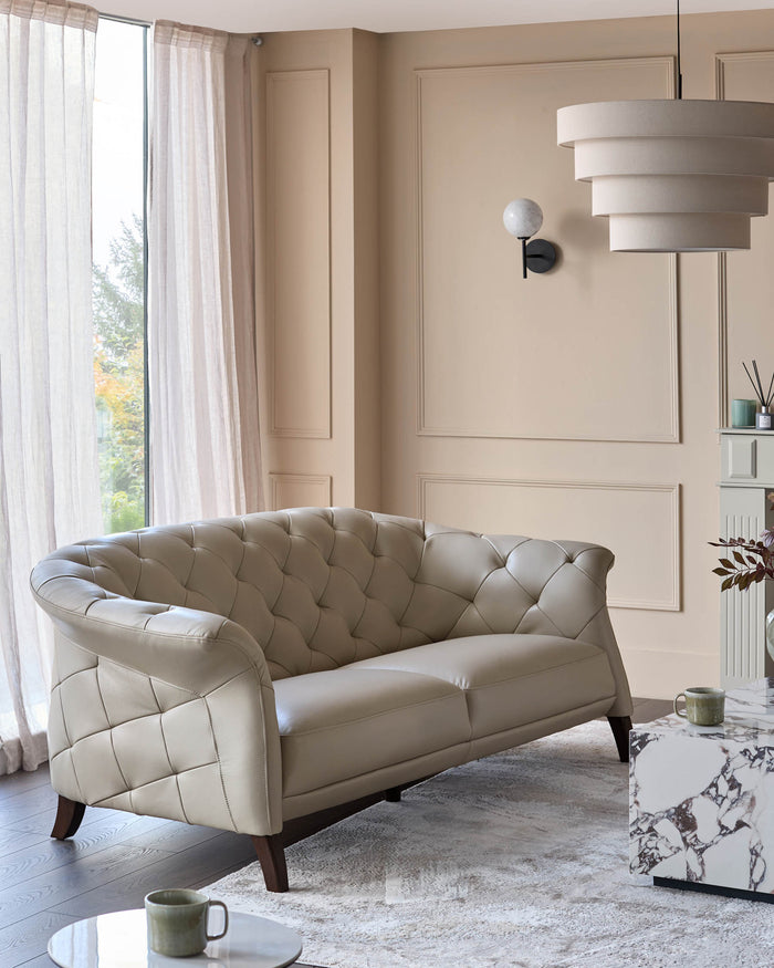 A stylish, tufted, leather sofa sits on a patterned rug, complemented by a marble-effect coffee table.