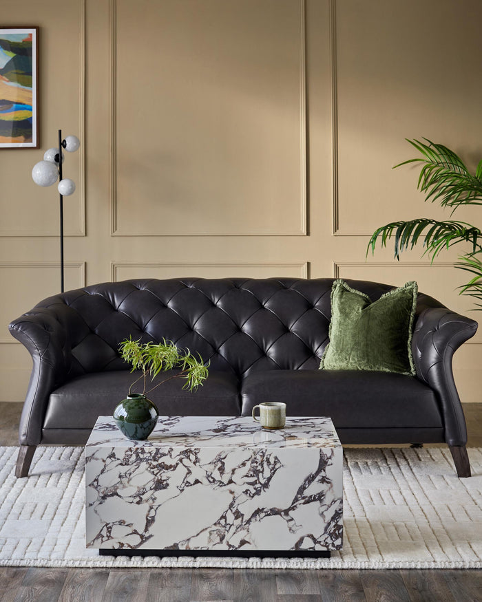 A luxurious black leather sofa complemented by a marble coffee table and a plush green cushion.