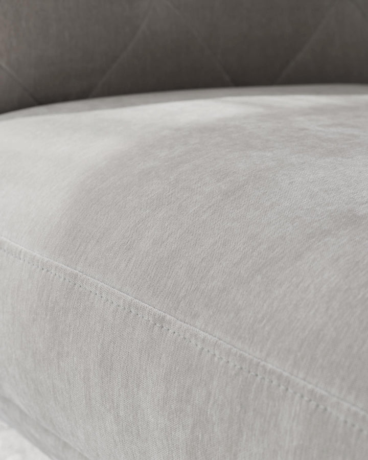 Close-up of a light grey sofa, showcasing the fabric and stitching detail.