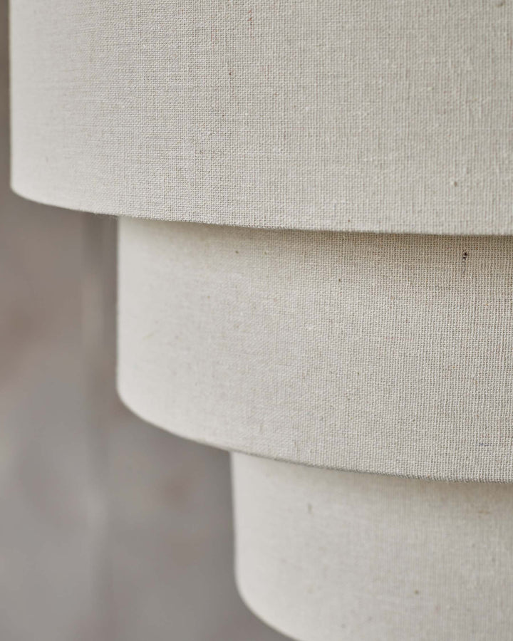 Close-up of a multi-tiered lampshade made of linen, showcasing its textured surface.