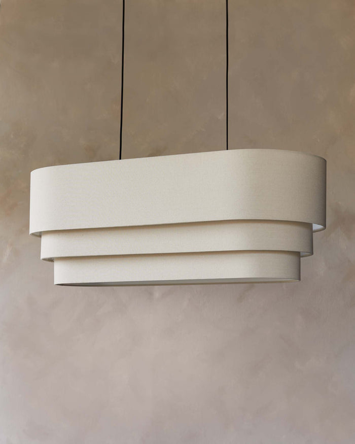 A stylish, tiered light fixture with a neutral shade hangs elegantly, illuminating the room with a soft, ambient glow.