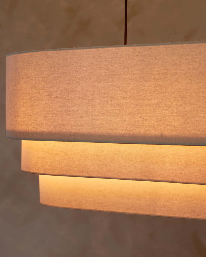 A three-tiered, fabric lampshade hangs from the ceiling, glowing softly and providing warm light to the room.