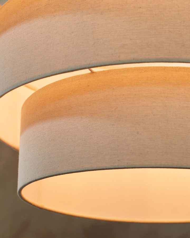 Close-up of a fabric lampshade, softly lit, showing neutral tones and textures. A modern, simple design element.