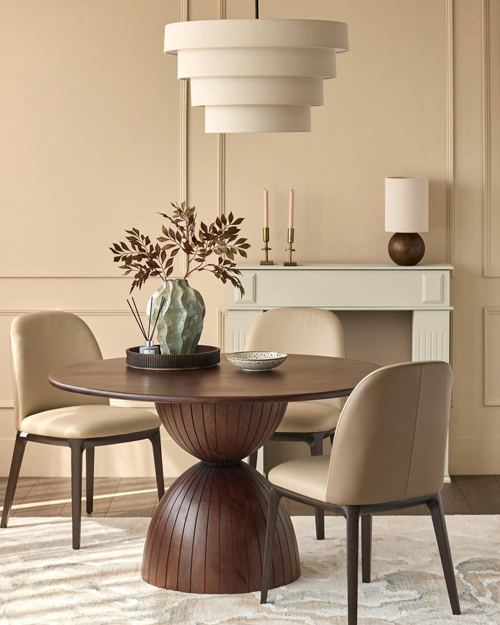 Dark mango wood round dining table with ribbed pedestal base, styled with cream chairs.