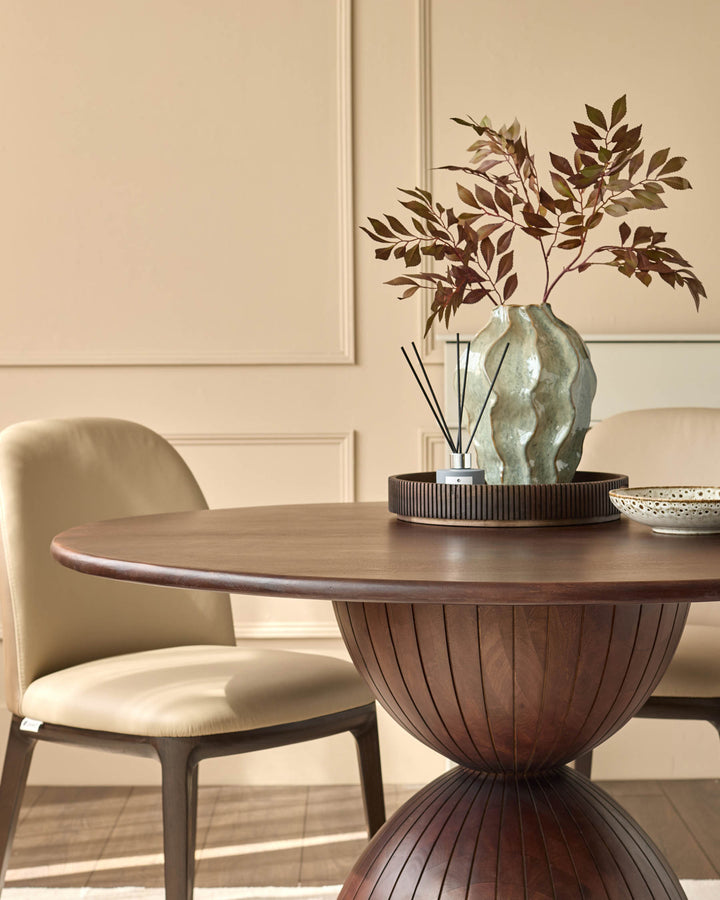 Malin 4-seater dining table in dark mango wood with pedestal base, shown with cream chair and styled decor.