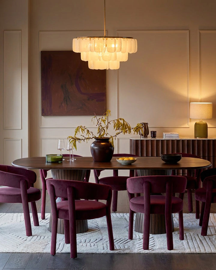Dark mango wood oval dining table with eight burgundy upholstered chairs in a modern dining room setting.