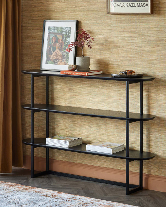 A contemporary black console table with three oval shelves, styled with books and decorative objects.