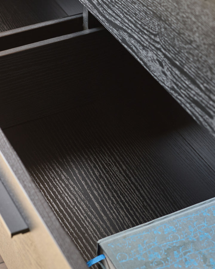 Dark wood drawer interior with textured finish and metal handle detail, partially open view.