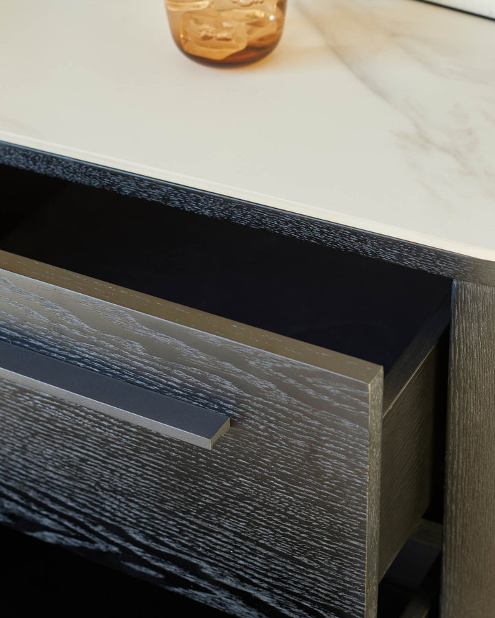 Dark wood bedside table with open drawer showing minimalist metal handle and white ceramic top surface.