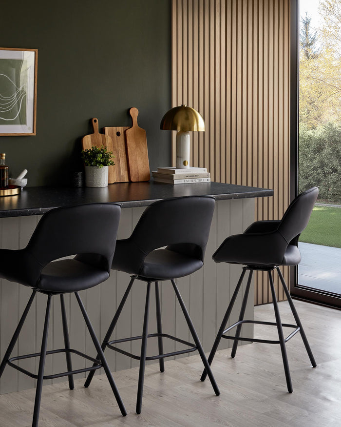 Three black bar stools sit at a kitchen island, offering modern seating in a stylish home interior.