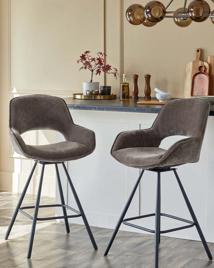 Two grey velvet bar stools with black metal legs sit at a kitchen island, radiating modern comfort and style.