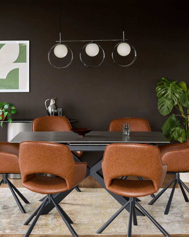 Hayden extending dining table in light grey ceramic with black metal X-frame base, styled with cognac leather chairs.