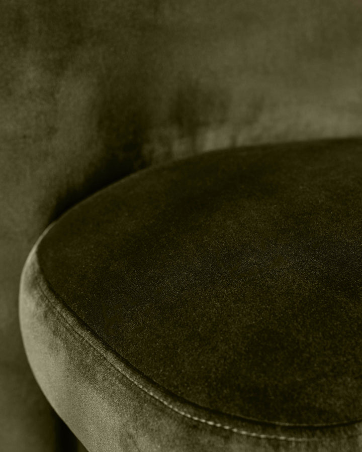 Mason dining chair in olive green velvet, close-up of curved seat and piping detail.