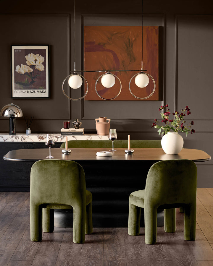 Mason dining chair in olive green velvet, rounded cylindrical back and seat, viewed in modern dining room setting.
