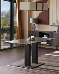 Contemporary dining area showcasing a sleek table with dual pedestal base, sideboard, and modern lighting for a stylish home.