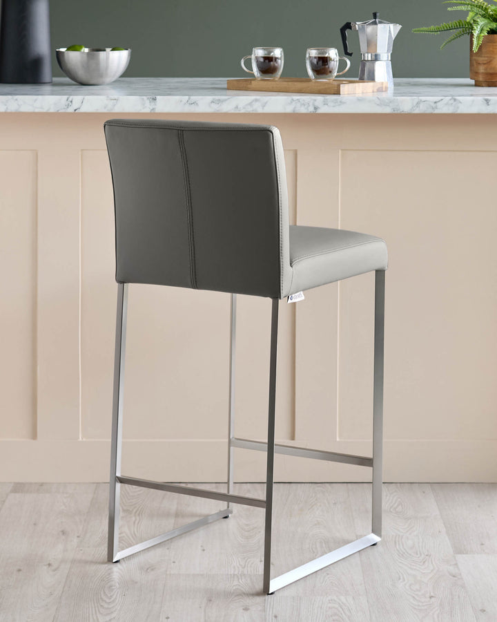 A modern grey bar stool with a metal frame sits in front of a kitchen counter.