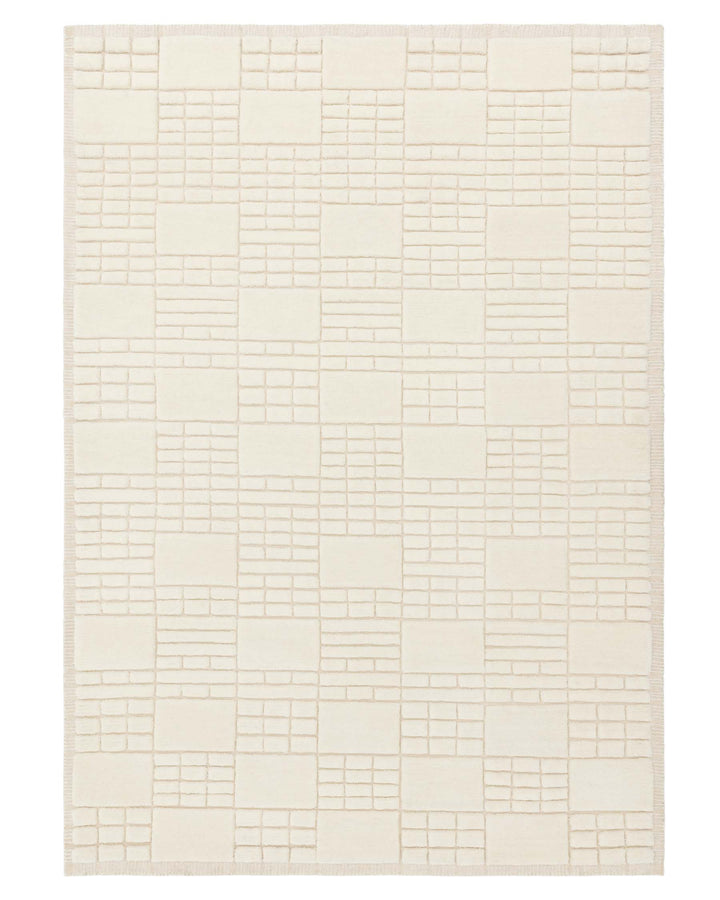 Cream-colored area rug with a textured geometric block pattern and fringe on the shorter edges.