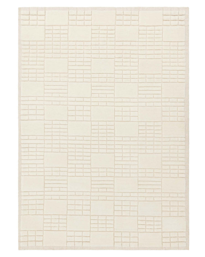 Ivory coloured area rug with a geometric pattern consisting of raised squares and rectangles against a flat background.