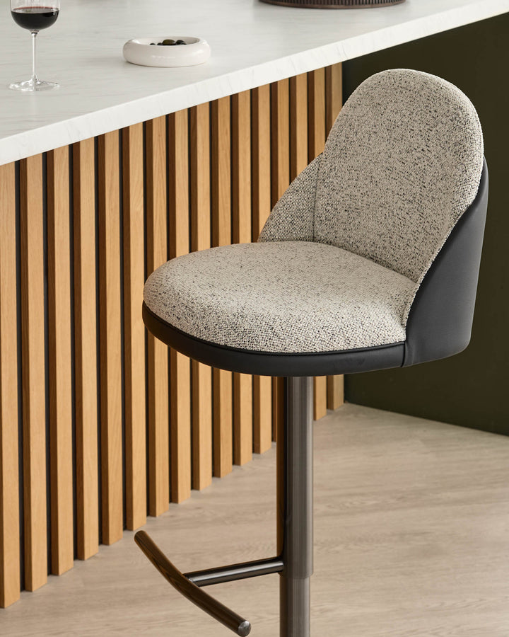 Myra gas lift bar stool with grey fabric seat, black faux leather back, and metal base at counter.