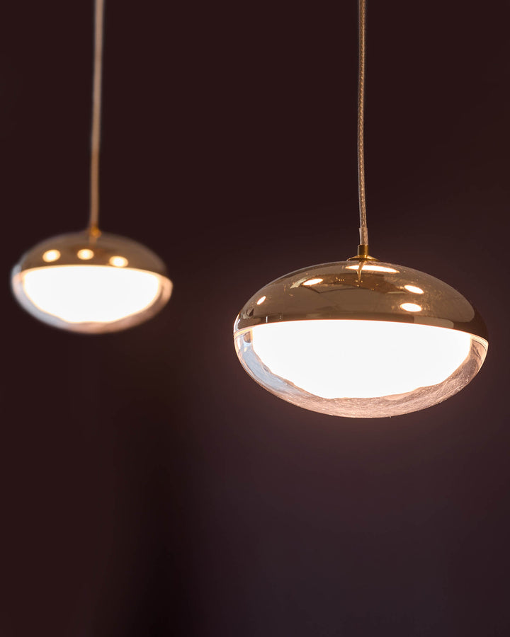 Nina 7 pendant lights in soft gold finish with frosted glass diffusers, shown against dark background.