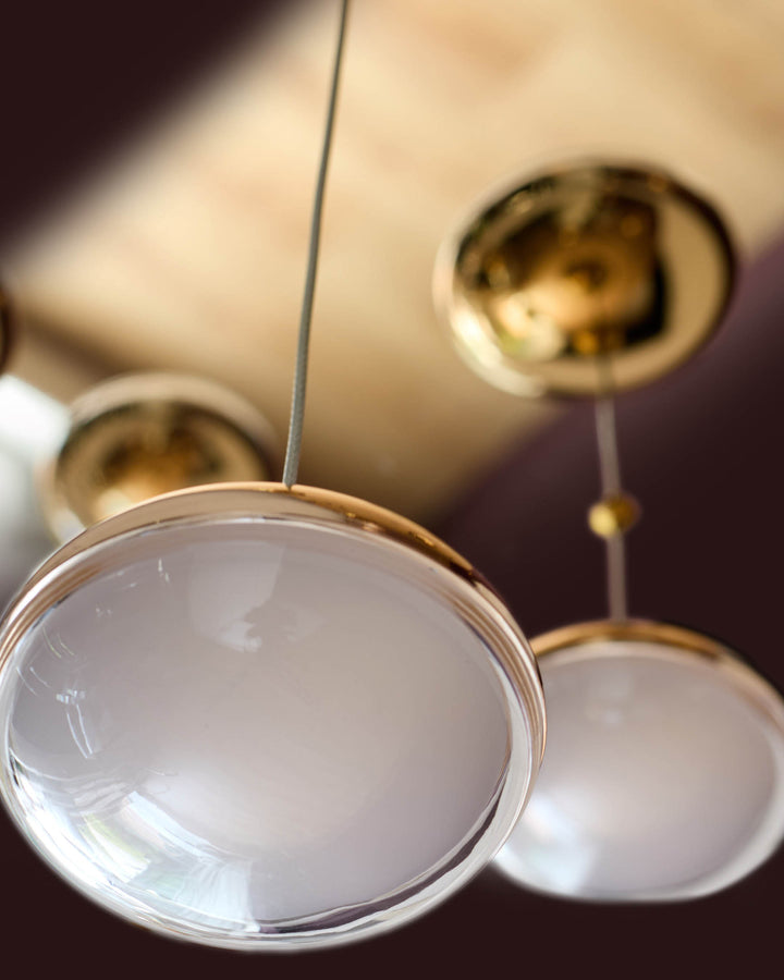 Nina 7 pendant light with soft gold finish and frosted glass dome shades, hanging arrangement view.