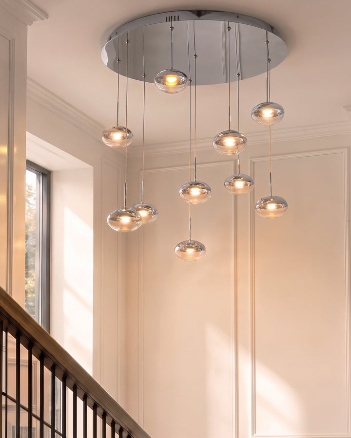 Nina 10-pendant light with clear glass shades and chrome finish, suspended from a round ceiling canopy above a stairwell.