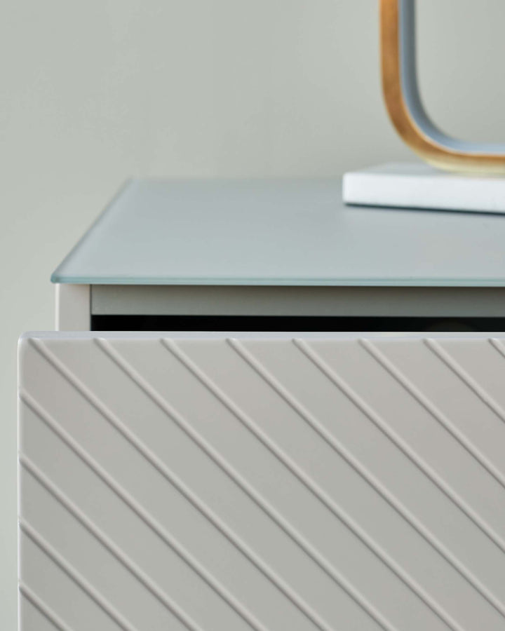 Close-up of a modern cabinet with a ribbed door and a light grey top. Minimalist and stylish furniture.