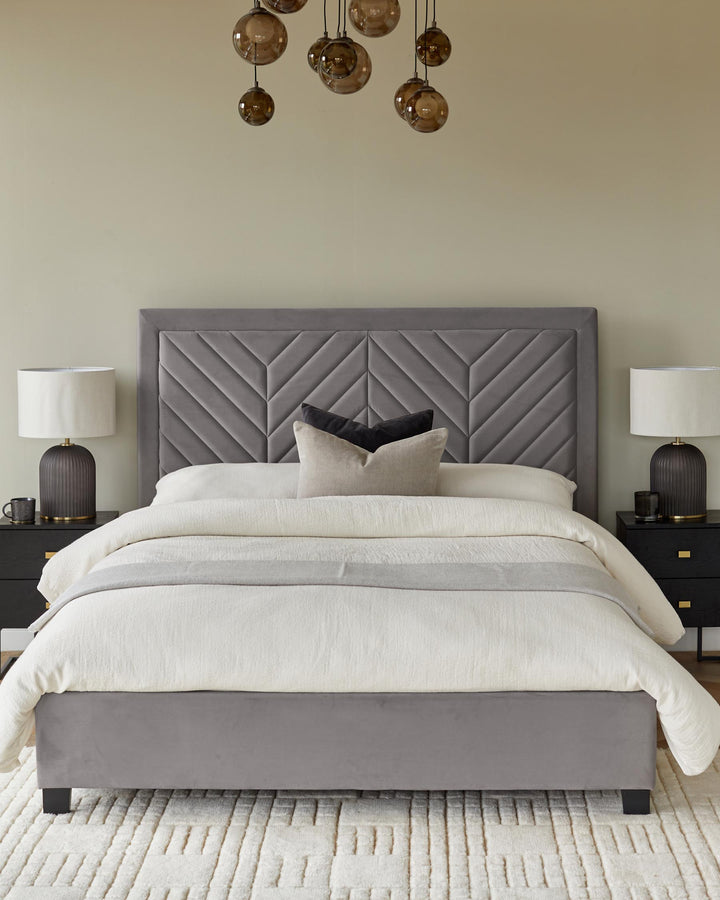 A stylish bedroom set featuring a grey upholstered bed frame, headboard, bedside tables, and table lamps.