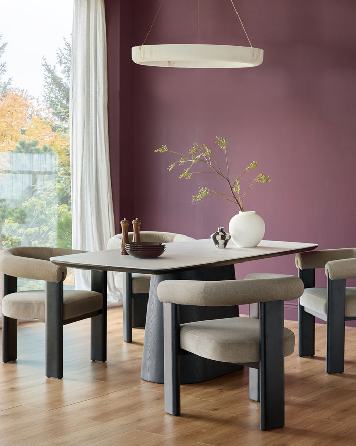 A modern dining room set featuring a light table with matching chairs and a striking circular light fixture.