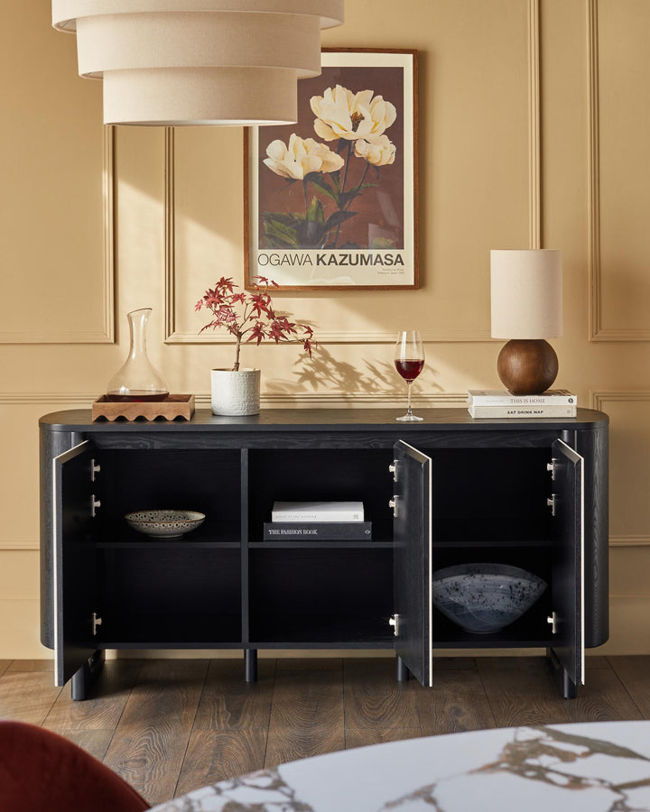 A stylish black sideboard with open doors, displaying elegant home decor accessories and a curated aesthetic.