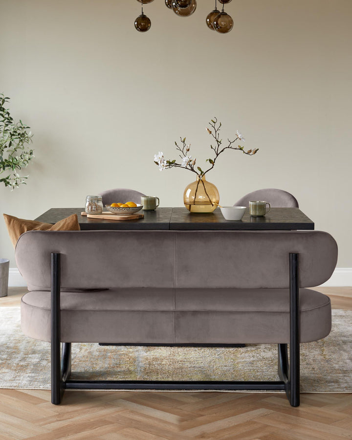 A stylish dining set featuring a brown velvet bench, a dark wood table, and elegant lighting above.