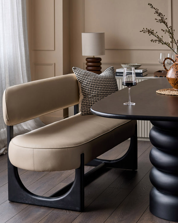 Orlan 3-seating dining bench with backrest in natural faux leather, black wooden frame, curved seat design in modern interior.