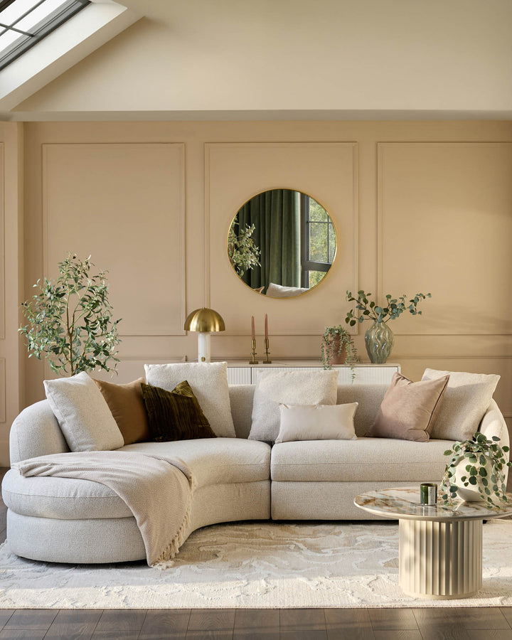 Ottilie left-hand corner chaise sofa in natural fabric, curved design with multiple cushions in a warm, neutral living room.