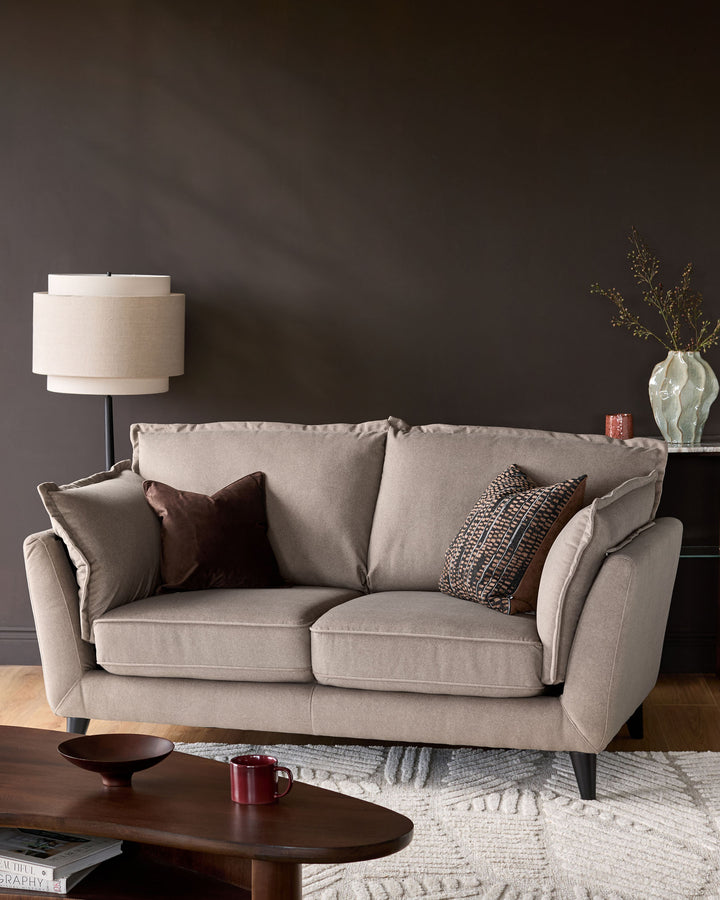 Otto 2-seater sofa in mocha fabric, shown in a styled living room setting with decorative pillows and neutral décor.