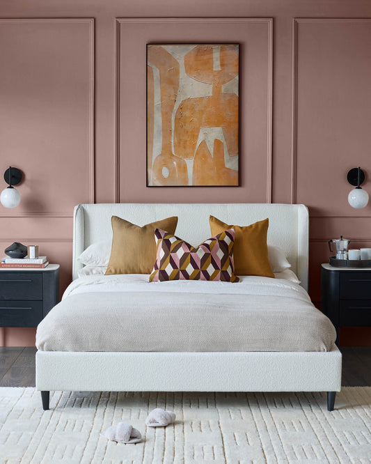 Bedroom features a bed with a neutral colour scheme, bedside tables, abstract art and slippers on a cream rug.