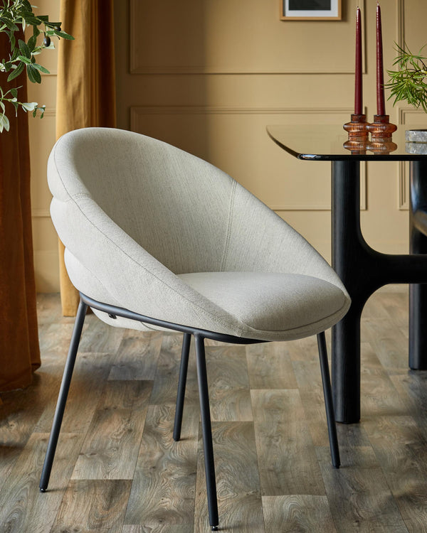 A modern chair with a light grey fabric seat and black metal legs, next to a table with candles.