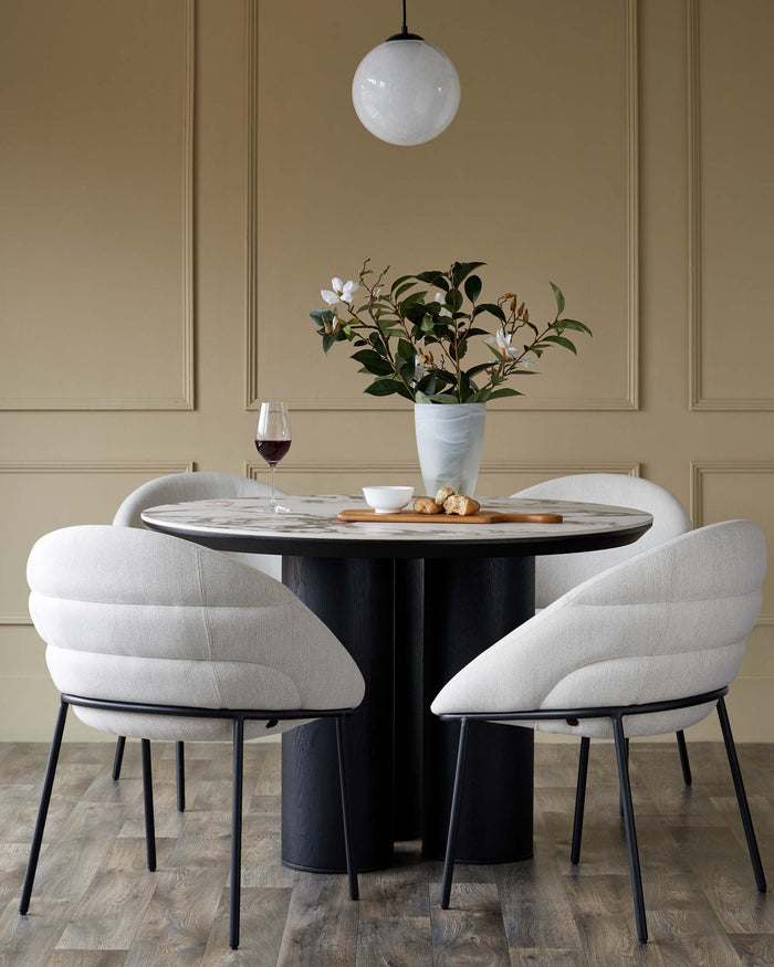 A round marble-topped dining table with grey cushioned chairs and black metal legs creates a contemporary and elegant dining space.