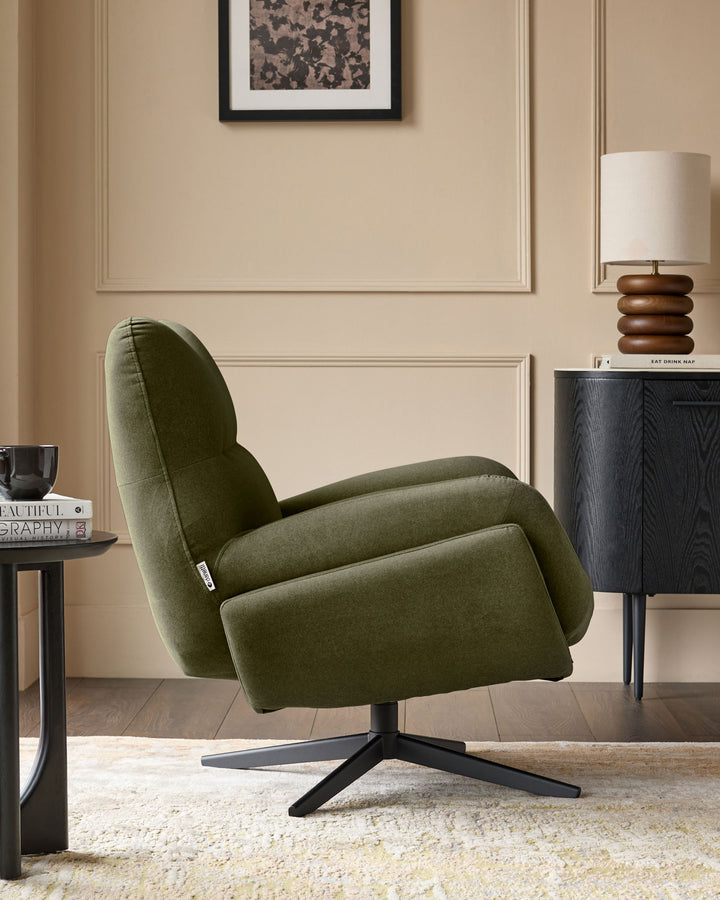 Olive green velvet accent chair with curved backrest and black four-star base, displayed in a styled living room setting.
