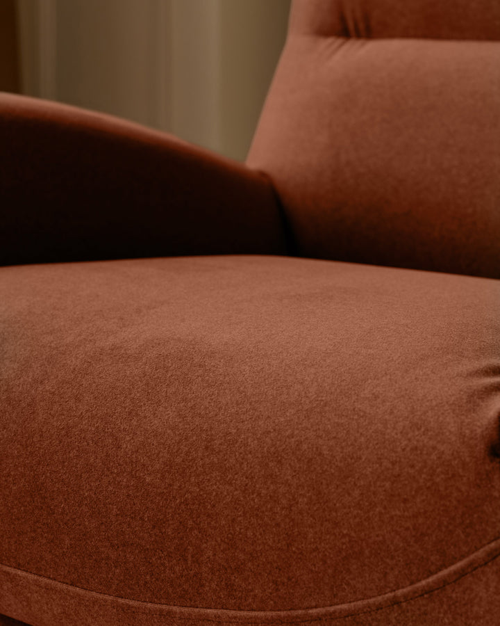 Piper accent chair in toffee red fabric, close-up detail showing seat cushion and curved armrest.