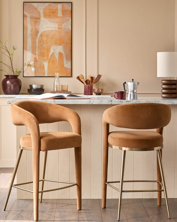 Two elegant brown bar stools with gold legs sit in front of a kitchen island, showcasing modern design and comfort.